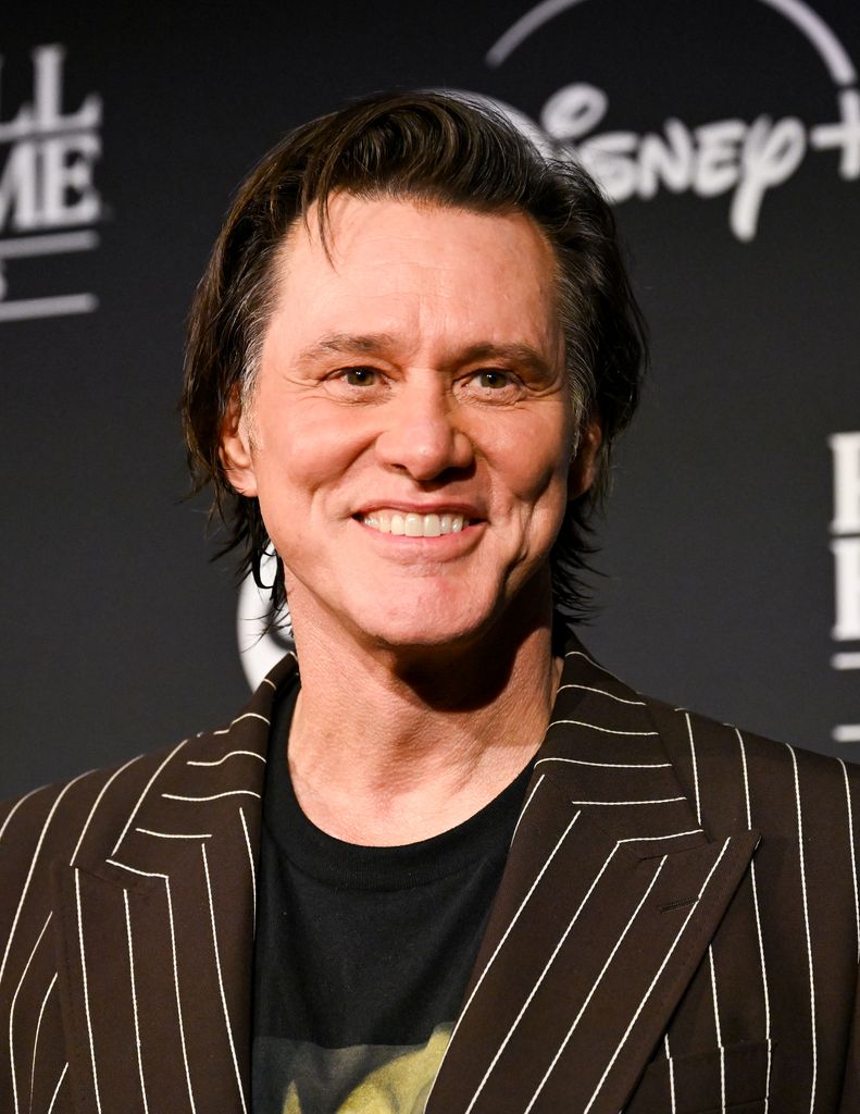 Jim Carey sourit et porte un blazer rayé lors de son intronisation au Rock and Roll Hall of Fame.