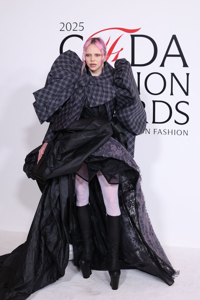 Slovak singer Adela attends the CFDA Fashion Awards  and poses on the red carpet wearing an oversized checked dress with long train, white tights and knee high boots.