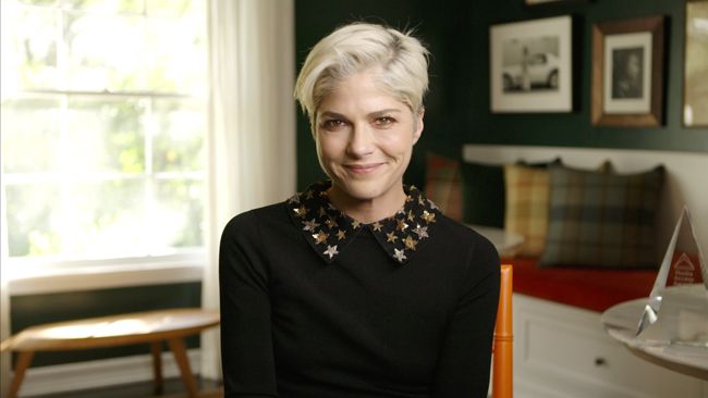 Selma Blair wearing a statement collared black top smiling at the camera 