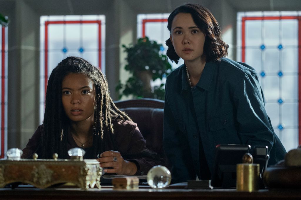 two teenage girls sitting at desk in dimly-lit office