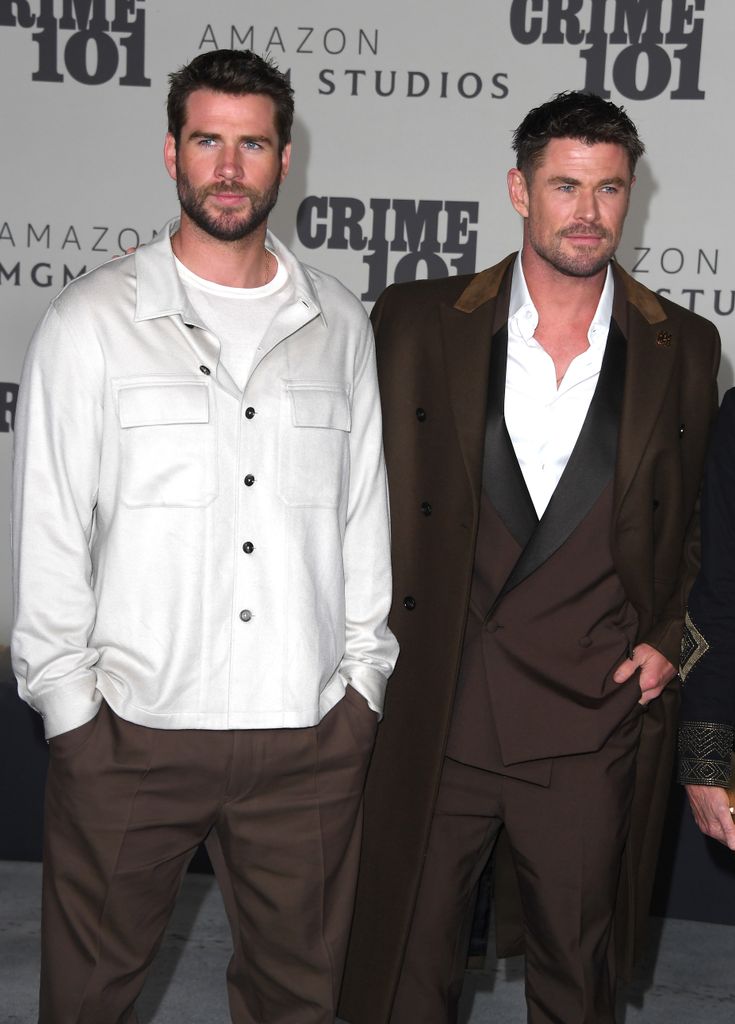 Liam Hemsworth en veste blanche et Chris Hemsworth en costume marron 