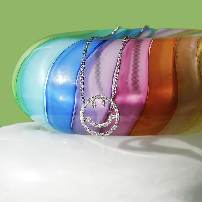 a diamond encrusted necklace on a rainbow hued glass pebble