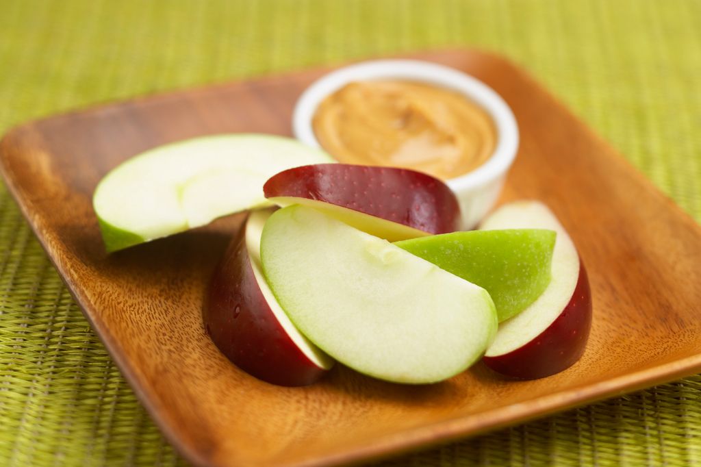 Apple slices beside nut butter in pot