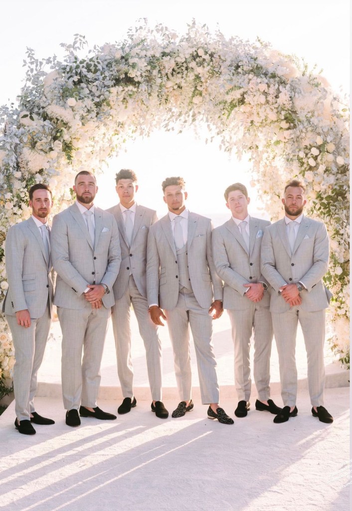 Travis Kelce (2L) stands with Patrick Mahomes (3R) and other groomsmen under a floral arch