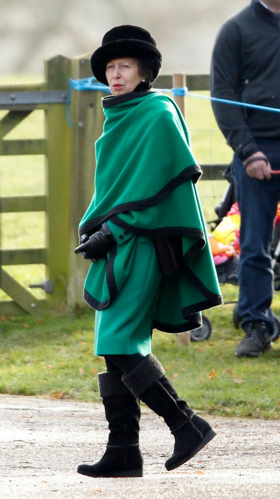 Princess Anne in black knee-high boots and emerald green cape