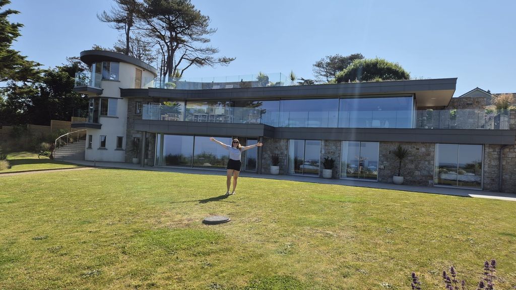 big cornwall house with a woman standing happily in front of it