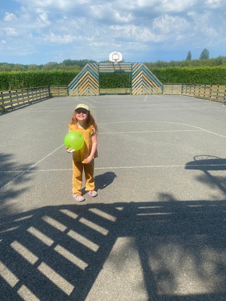 Girl holding green ball on an outdoor basketball court