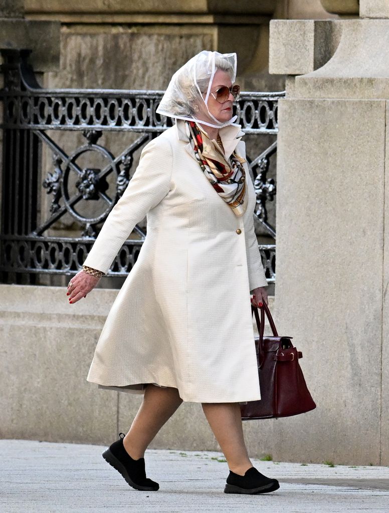 woman in cream trench coat and glasses walking down street