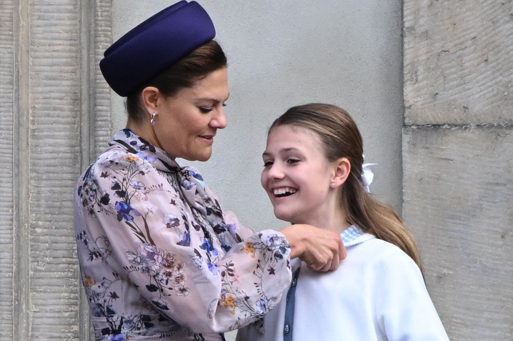 Crown Princess Victoria fixes Princess Estelle's collar on the balcony