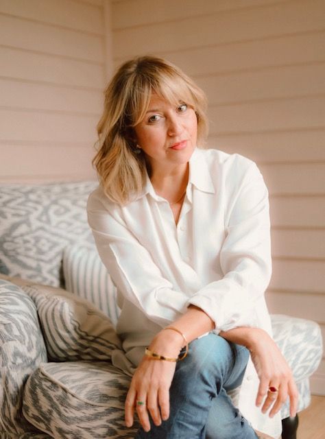 Woman sitting on a patterned chair, wearing white shirt and blue jeans 