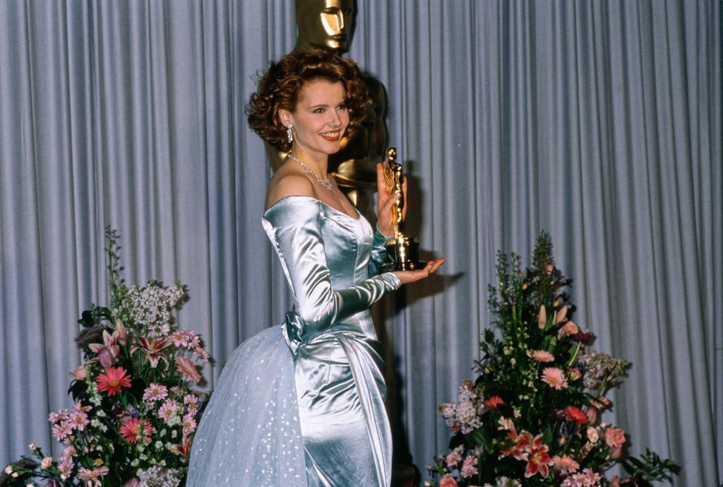 American actress Geena Davis wearing an off-shoulder blue evening gown, in the press room of the 61st Academy Awards, held at the Shrine Auditorium in Los Angeles, California, 29th March 1989. Davis holds her 'Best Supporting Actress' award received for her performance in 'The Accidental Tourist'.