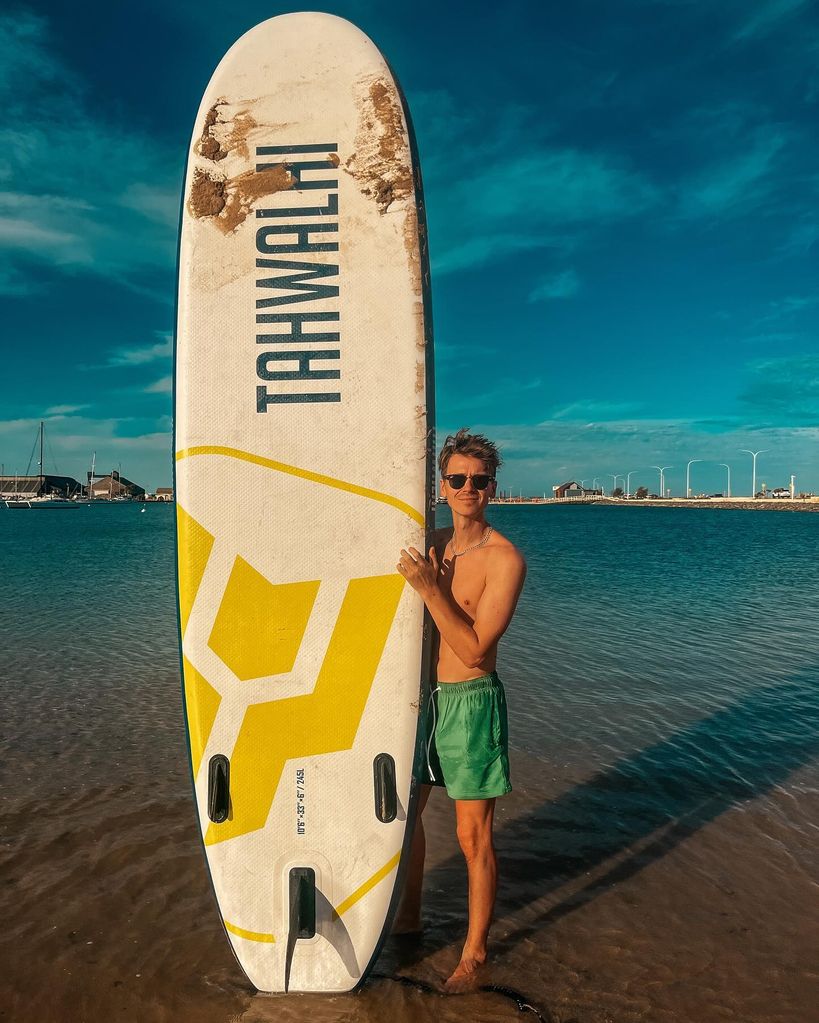 Joe standing with a surfboard