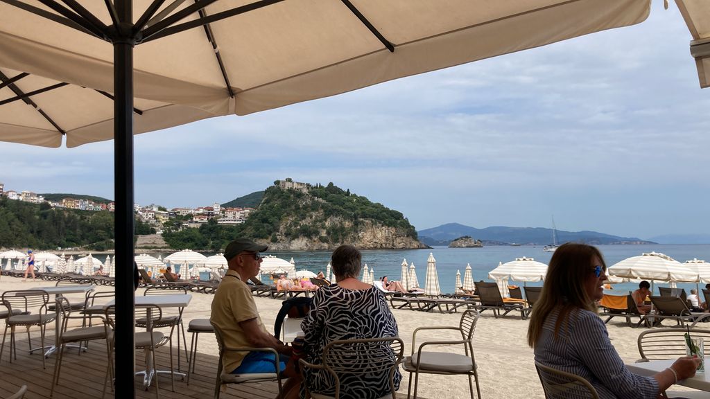 View of a beach and sea with a village on a peninsula in the background