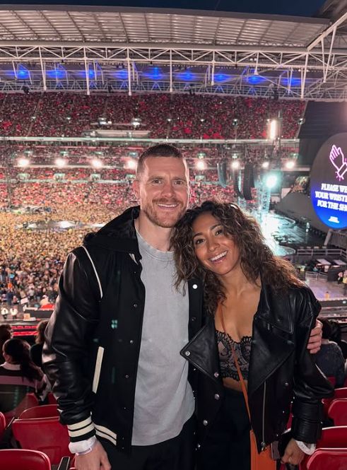 Karen Hauer leaning into Simon Davidson at a Coldplay concert