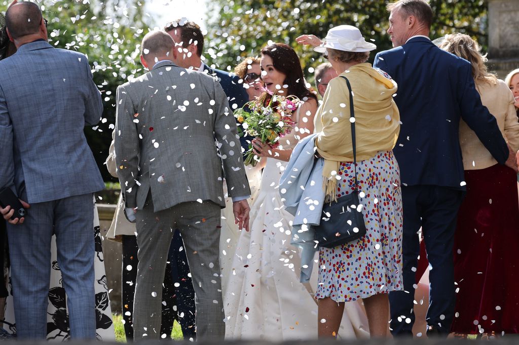Wedding guests throwing confetti over Michelle Dockery and Jasper Waller-Bridge