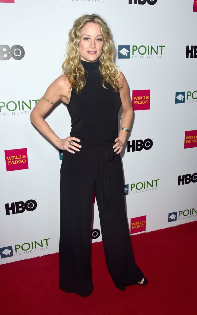 Teri Polo se tient les mains sur les hanches dans une combinaison noire dos nu sur le tapis rouge.