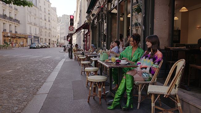 Emily and Mindy sit outside cafe near Emilys apartment in Paris