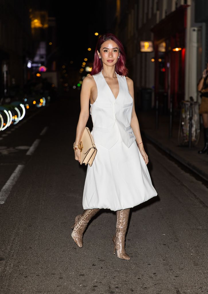 Heart Evangelista wears white dress, beige bag, boots outside Victoria Beckham during the Womenswear Fall/Winter 2025/2026 as part of Paris Fashion Week on March 07, 2025 in Paris, France.