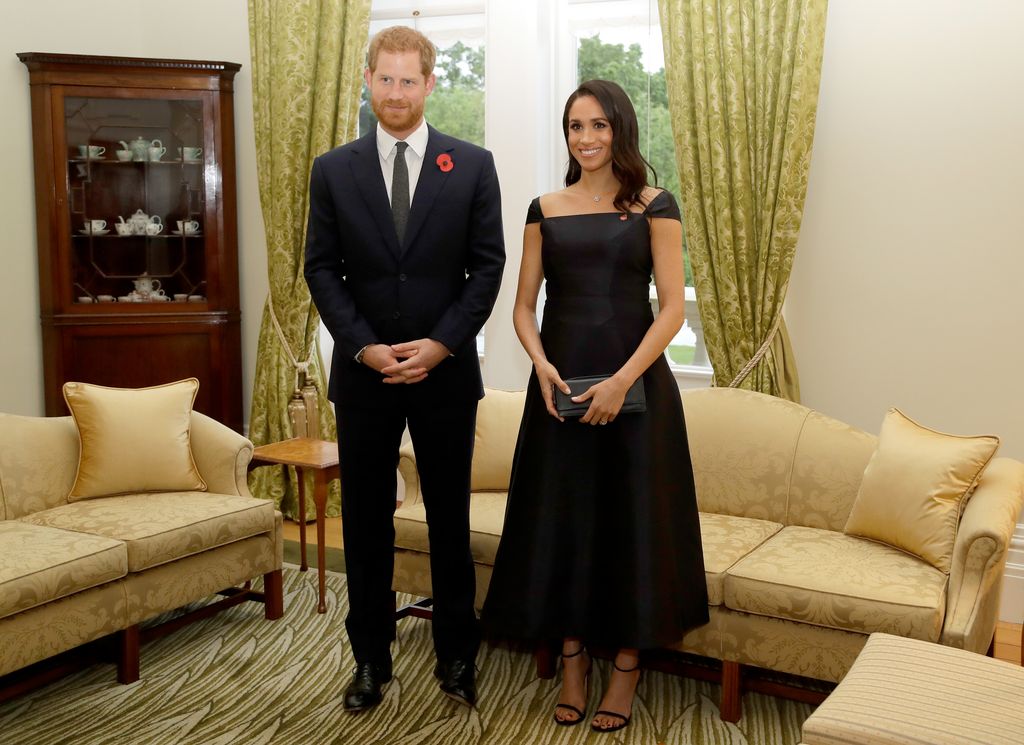 Meghan in black dress beside harry in suit