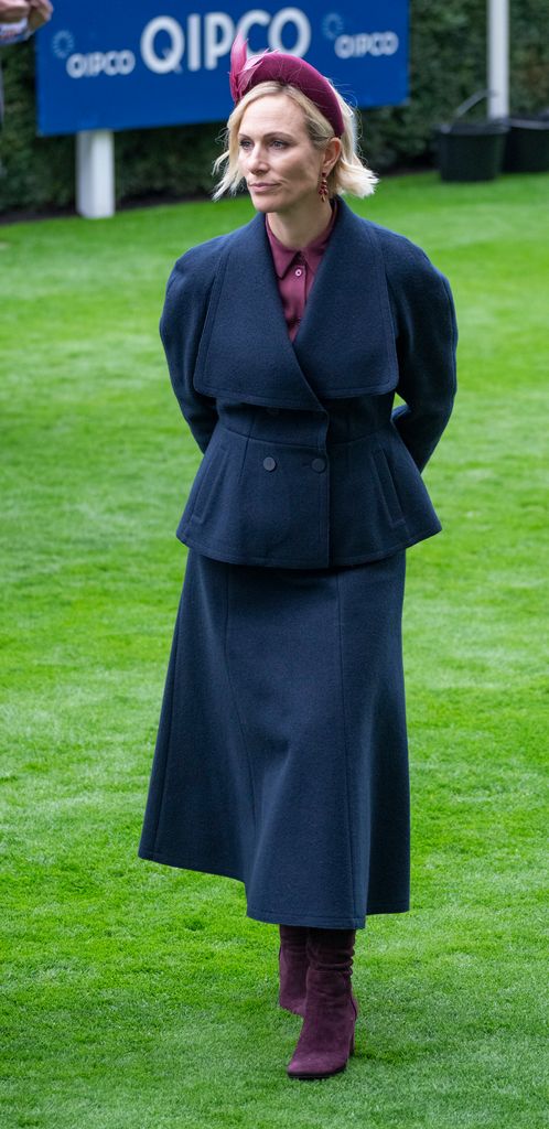 Zara Tindall on grass in navy coat and skirt