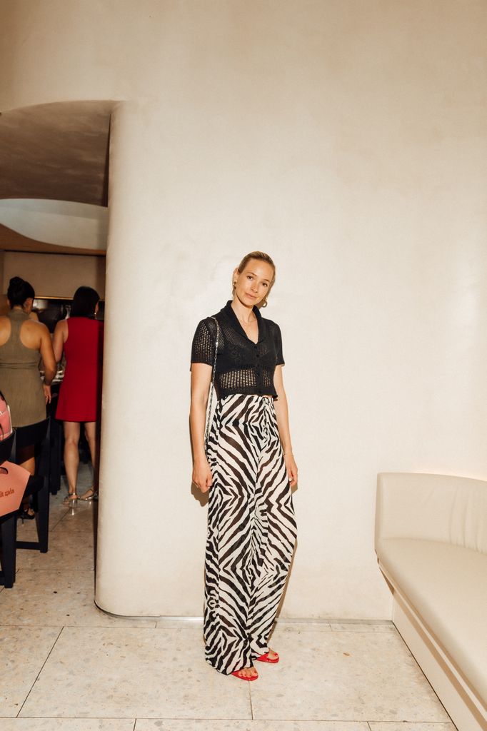 Model Anna Sophie Mungenast pairs a sheer zebra-print maxi skirt with a cropped black knit top and red sandals, bringing breezy, modern elegance to Cult Gaia’s intimate Notting Hill dinner party celebrating fashion and creativity.