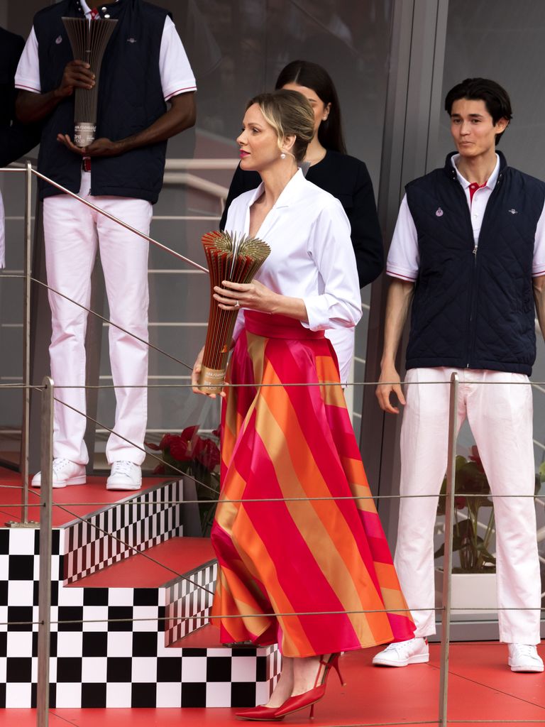 Princesa Charlene en una ropa a rayas y una camisa blanca que sostiene las flores