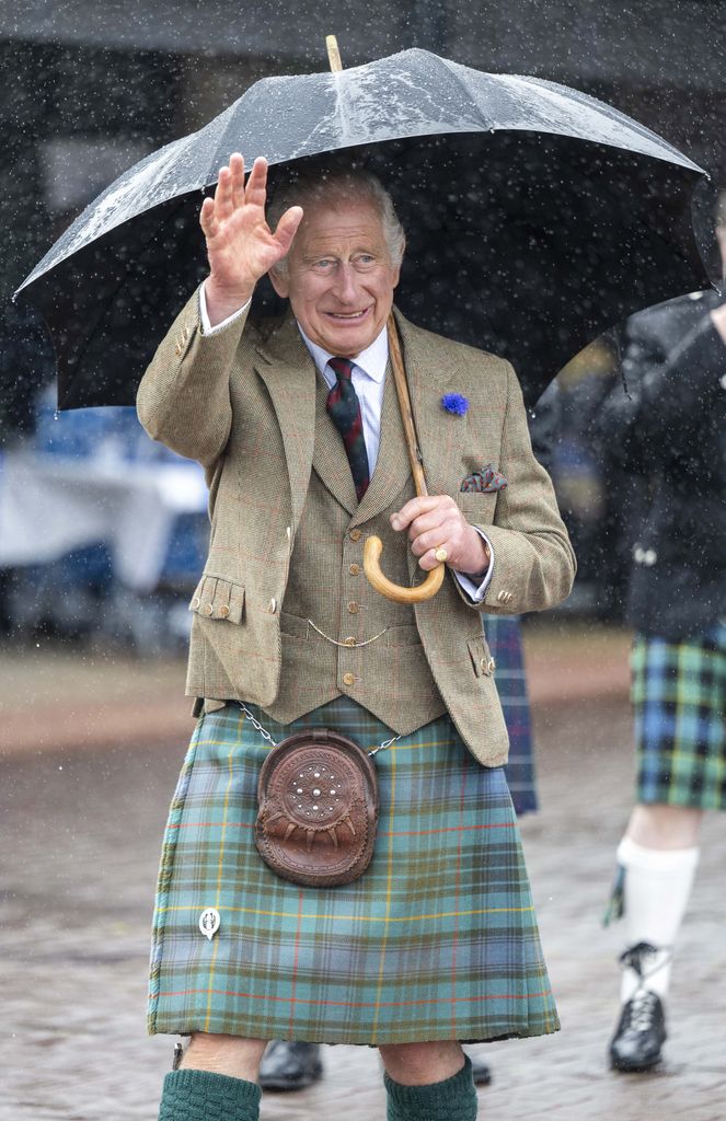 King Charles wearing a kilt and holding an umbrella as he arrives at 8 Doors Distillery