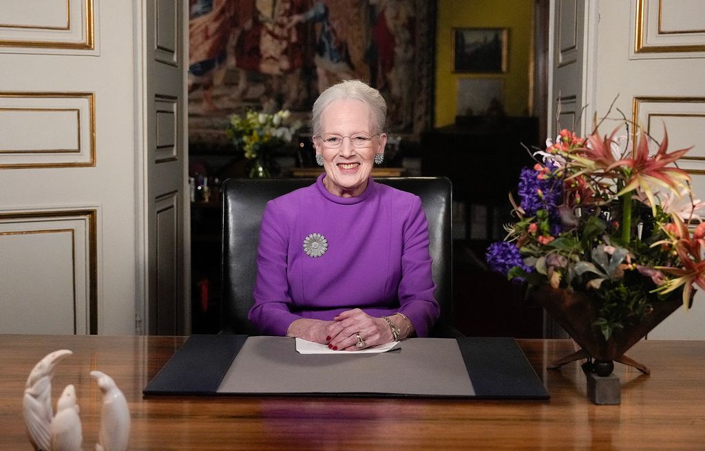 Queen Margrethe sitting at table in purple