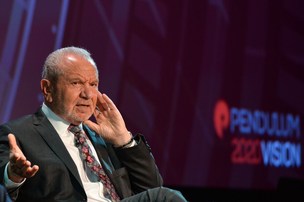 Alan Sugar s'exprimant sur scène en costume-cravate 