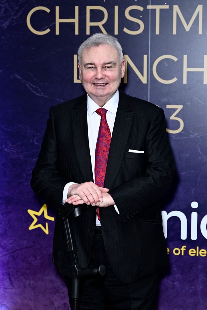 Eamonn Holmes in a black suit with a black cane