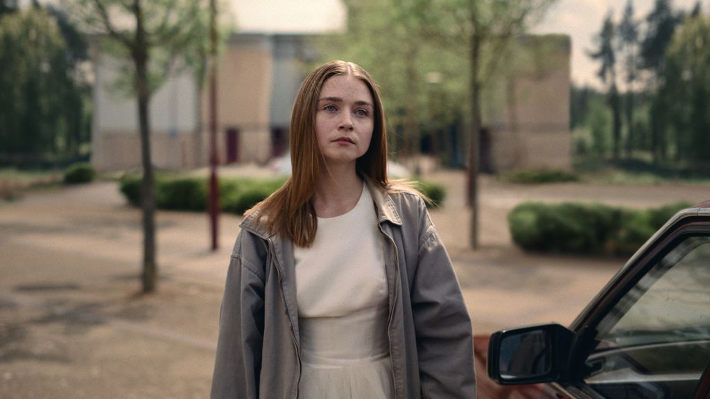 Jessica Barden in The End of the F***ing World looking sad, wearing a white dress and grey cardigan