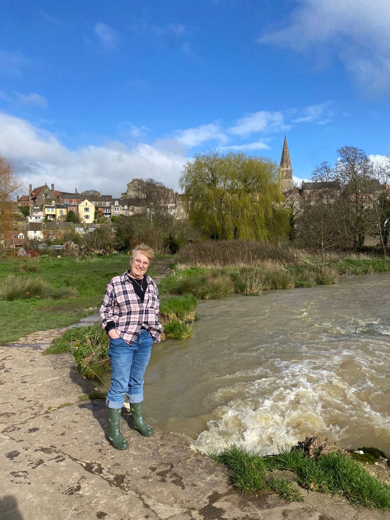 Woman standing by a river in wellies 