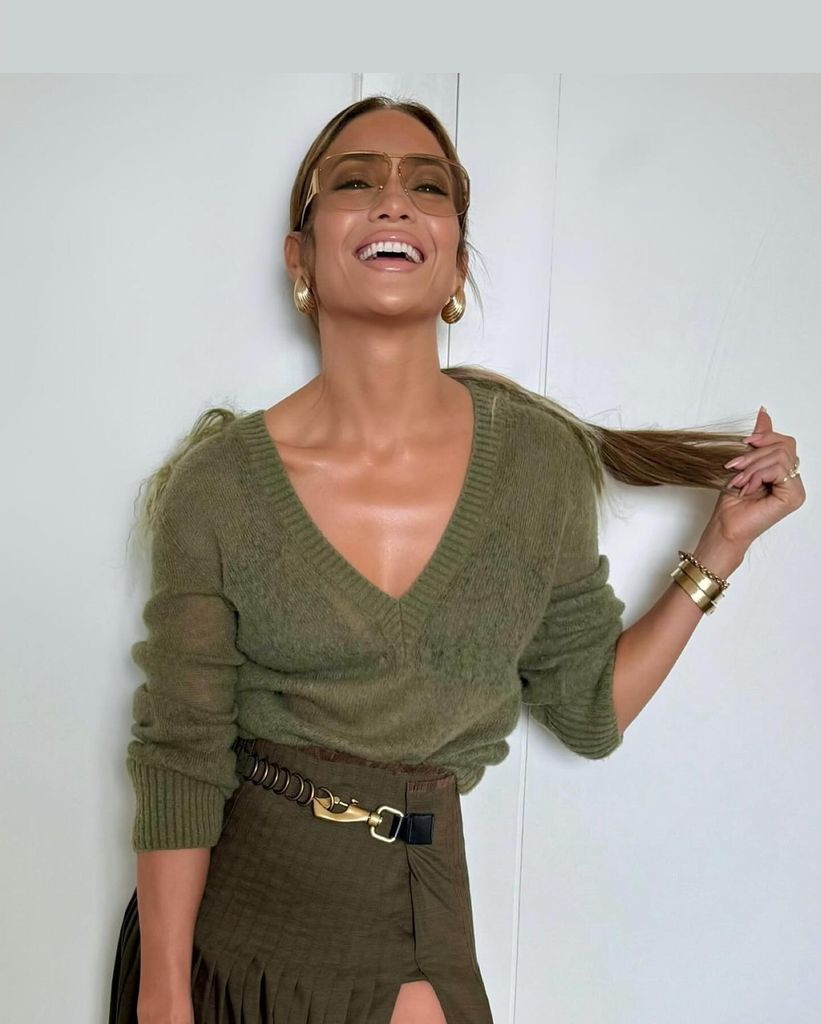 Jennifer Lopez smiling widely in an olive green top