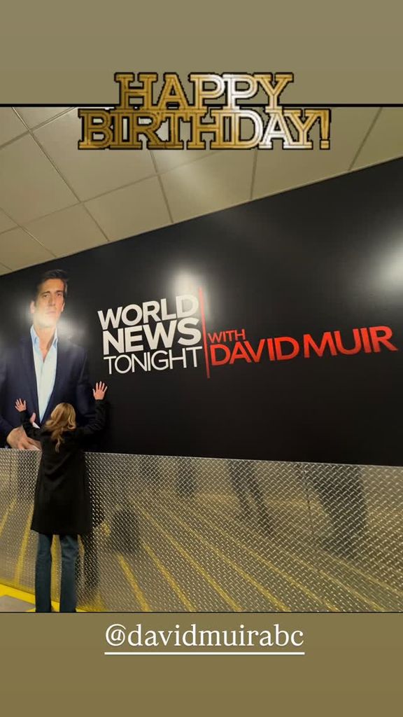 Kelly Ripa embraces a poster of David Muir in the ABC building, shared on Instagram for the latter's birthday