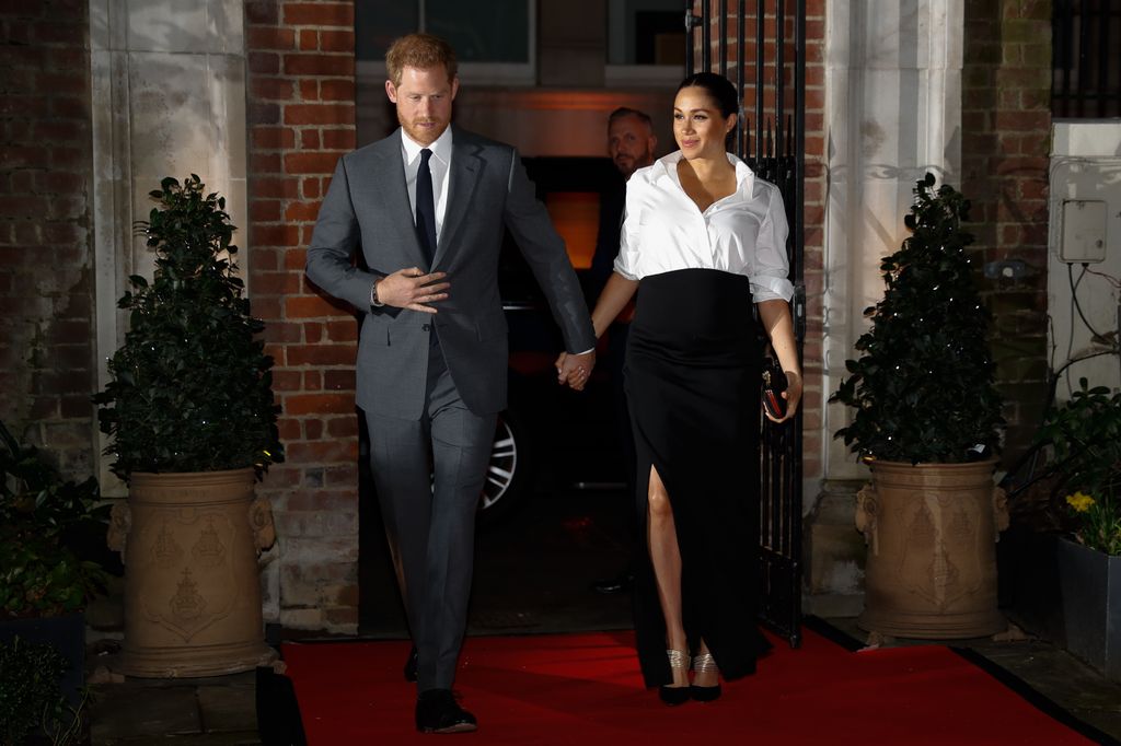 Prince Harry and Meghan Markle stepping onto red carpet at night