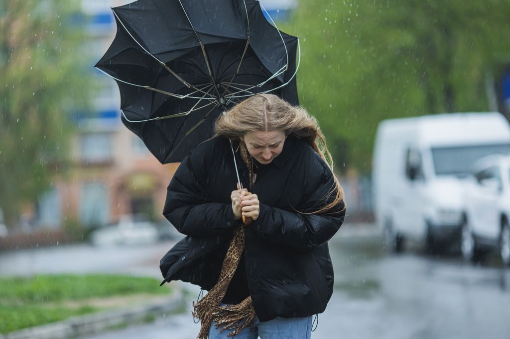 Une femme marchant avec un parapluie retourné