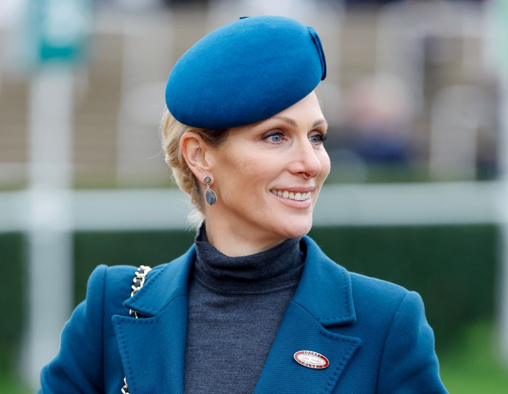 Zara Tindall looking to right in petrol blue hat and coat