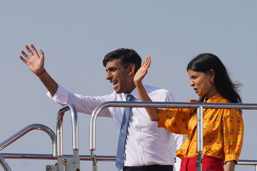 Britain's Prime Minister Rishi Sunak (L) and his wife Akshata Murty wave as they board a plane following the G7 Leaders' Summit in Hiroshima on May 21, 2023.