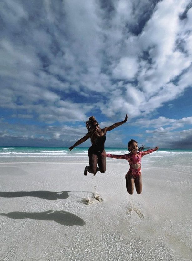 Serena Williams a nd young girl jumping into the air on a beach