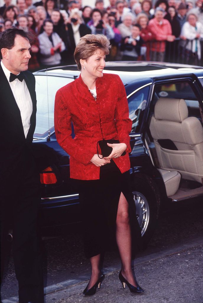 Sophie exiting car in red jacket and black skirt 
