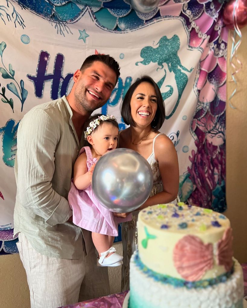 parents holding daughter at first birthday party