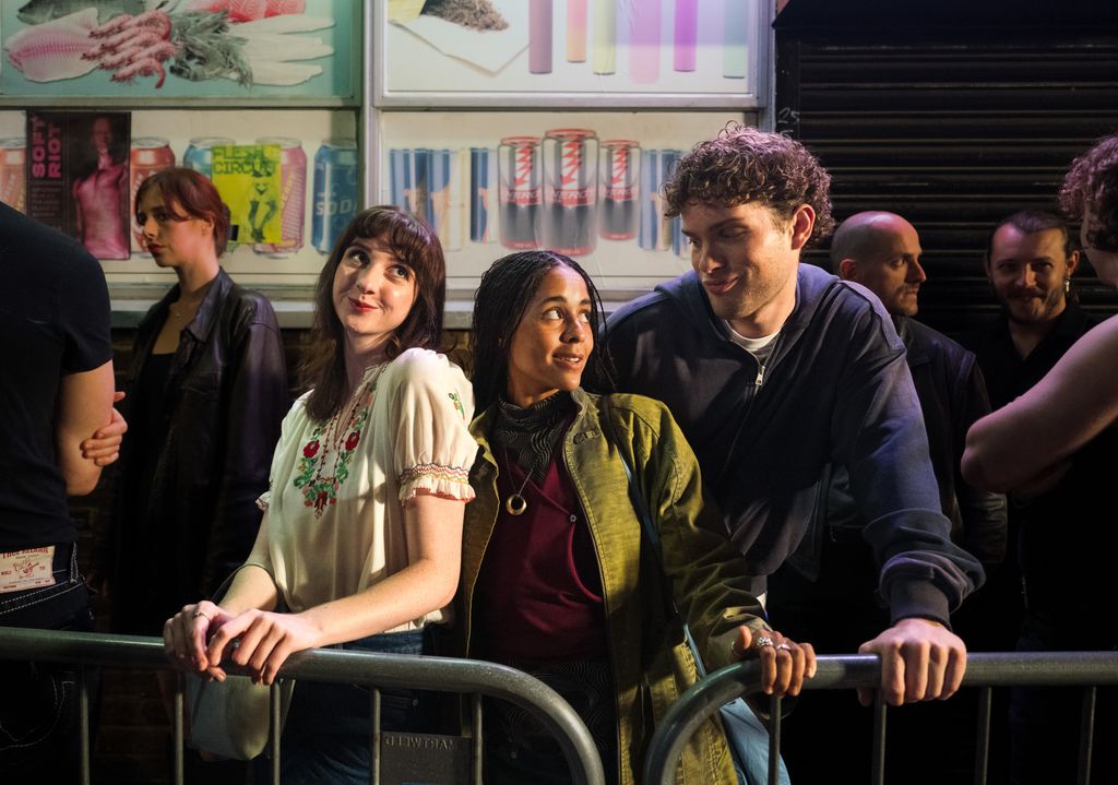 three young people standing in queue outdoors