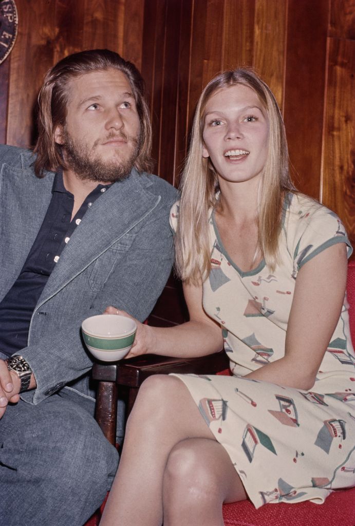 Jeff Bridges, wearing a grey blazer over a black shirt with an open collar, and his partner, Susan Geston, who wears a dress adorned with matchbook motifs, attend the Golden Apple Awards, at the Beverly Hills Hotel in Beverly Hills, California, December 1975