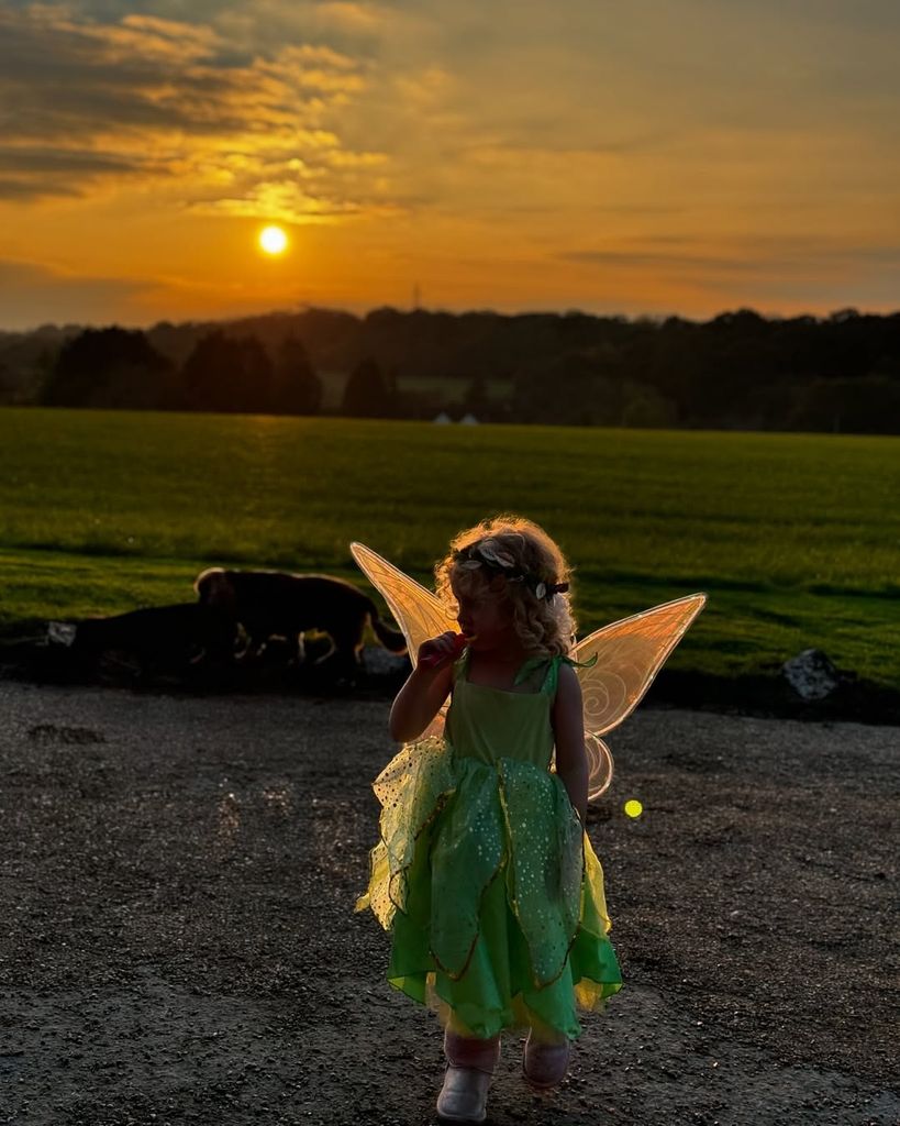 Stacey's daughter Rose in a Tinkerbell standing outside in front of sunset