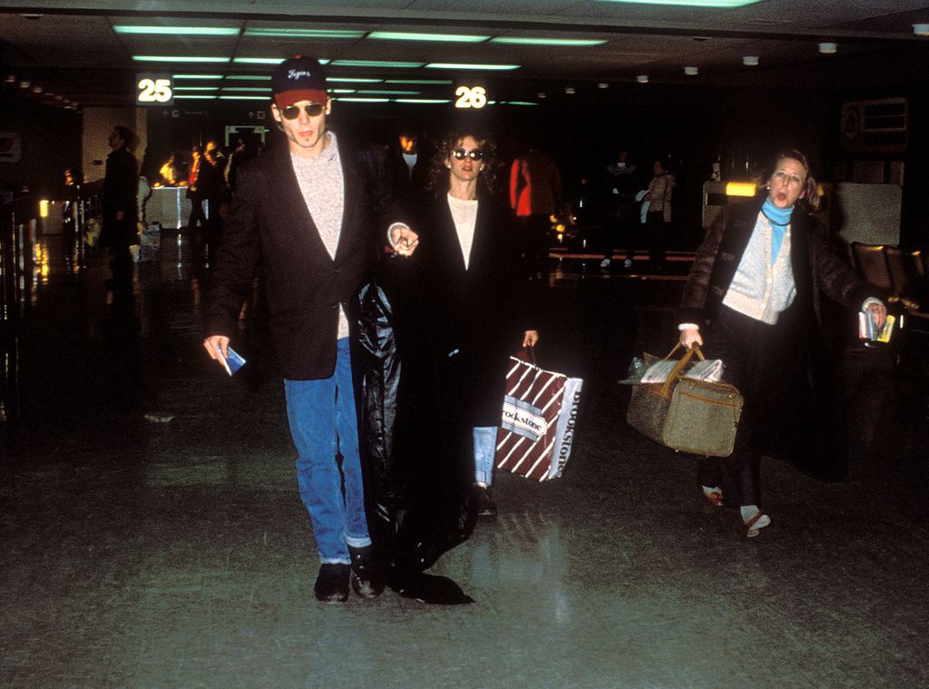 Johnny Depp in a cap walking next to Jennifer Grey