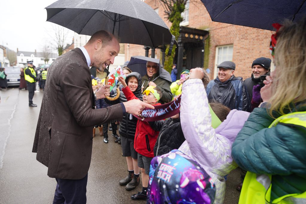 Le « doux » prince William a la meilleure réaction face à un enfant timide dans une nouvelle vidéo 2 Le prince William, prince de Galles, se met à l'abri de la pluie sous un parapluie tout en rencontrant des membres du public lors d'une visite des jardins suspendus, un espace dédié à nourrir la résilience et la créativité des communautés, le 26 février 2026 à Newtown, au Pays de Galles.