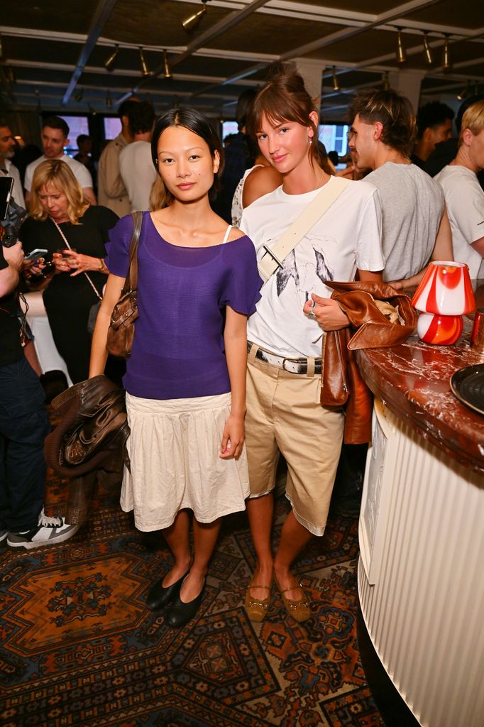 Mia Regan and Minmie Sangsawang pose at Louie London during the Choose Love launch. Mia sports jorts and a graphic tee, while Minmie wears a purple knit top and cream skirt combo.
