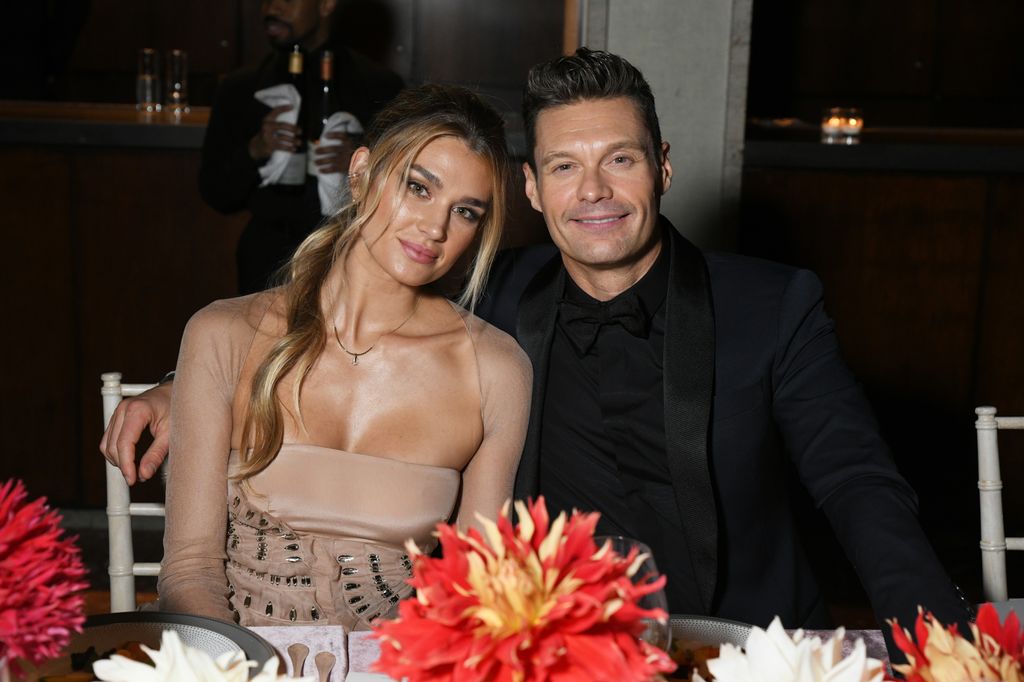 Shayna Taylor and Ryan Seacrest smiling at table 