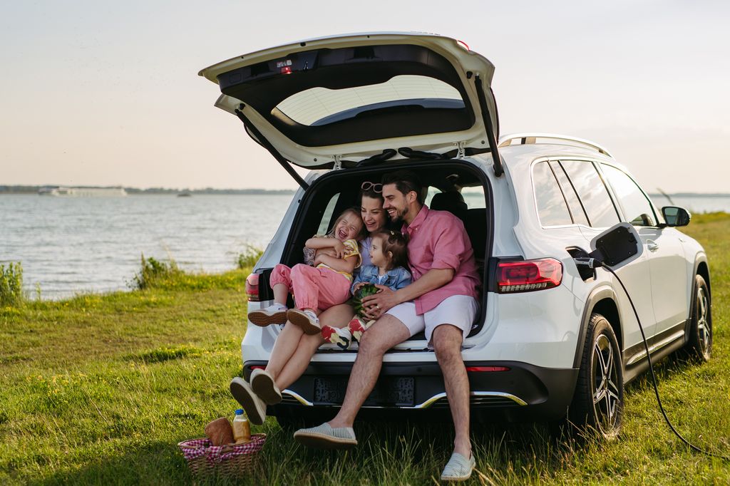 Happy family on the summer beach holiday sitting in the car trunk
