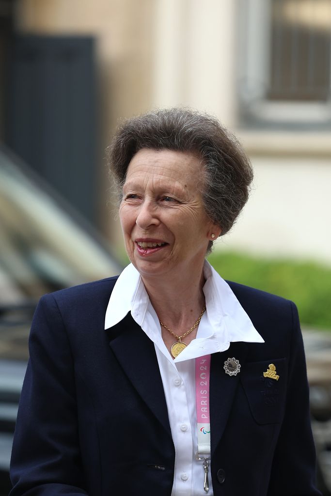 Princess Anne smiling in a white shirt and blazer